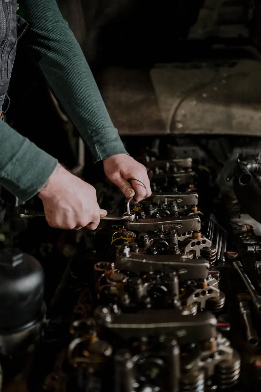 A technician's hands tightening a part on an engine